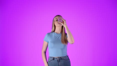 Caucasian-blonde-woman-drinks-water-from-glass-clean-bottle-studio-infinite-chroma-background-shot,-young-blonde-attractive-lady