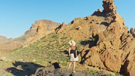 Tourist-woman-with-summer-hat-immersed-in-Teide-National-Park-rocky-landscape