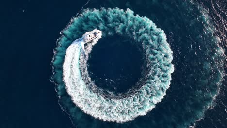 Top-down-drone-shot-of-luxury-yacht-driving-in-a-circle-at-sea-while-zooming-out