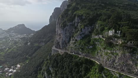 A-serpentine-road-along-the-cliffside-of-capri,-italy-with-lush-greenery,-aerial-view