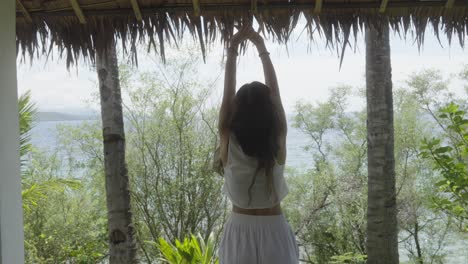 Woman-doing-morning-stretches-on-tropical-hotel-terrace-overlooking-the-sea