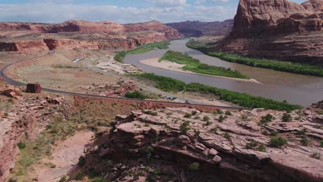A-4K-drone-shot-of-steep-cliffs-and-a-railroad-track-running-along-the-Colorado-River,-cutting-through-the-unique-and-rugged-desert-landscape-near-Moab,-Utah