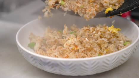 Chef-dumps-freshly-prepared-crab-fried-rice-onto-dish,-slow-motion-close-up-4K