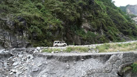 SUV-Offroad-Car-Driving-Tourists-on-Narrow-Mountain-Dirt-Road-to-Jomsom-in-Kali-Gandaki-Gorge-in-Central-Nepal---Aerial-side-tracking
