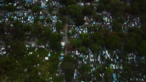 Aerial-tilt-shot-over-the-Manila-South-Cemetery-revealing-the-Makati-skyline,-in-Philippines