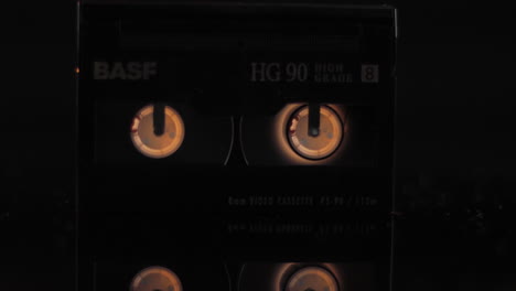 Vintage-BASF-8mm-Video-Cassette-Tape,-Spinning-Close-Up-on-Black-Background