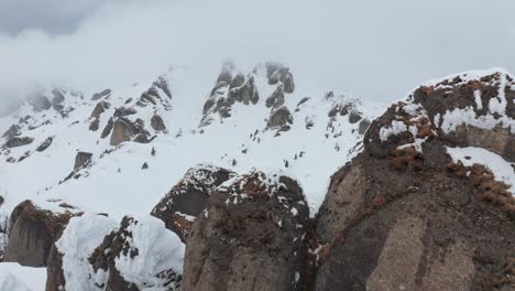 Snow-capped-Ciucas-Mountains-peaks-emerging-through-clouds,-dramatic-winter-landscape