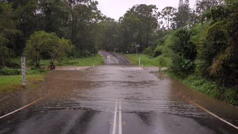 Gold-Coast,-Queensland,-16-February-2024---Wide-shot-of-flooding-across-Hardy's-Road-in-Mudgeeraba-after-heavy-rains-continue-to-lash-South-East-Queensland,-Australia