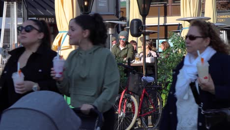 Vista-Cercana-De-La-Gente-Caminando-Junto-A-Los-Clientes-Sentados-En-El-Bar-Al-Aire-Libre-En-Estocolmo