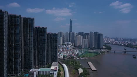 Ho-Chi-Minh-City,-Saigon-River-and-Binh-Thanh-skyline-on-sunny,-clear-day-featuring-landmark-building-from-drone-crane-shot