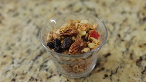 Mix-of-different-nuts-and-raisins-in-a-glass-cup,-close-up-shot