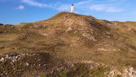 Aerial-view-tropical-island-with-lighthouse-on-top-of-hill,-caribbean-sea-background