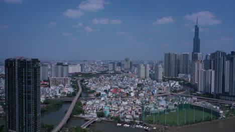 Ho-Chi-Minh-City,-Saigon-River-and-Binh-Thanh-skyline-panorama-on-sunny,-clear-day-featuring-landmark-building-from-drone-orbit-shot