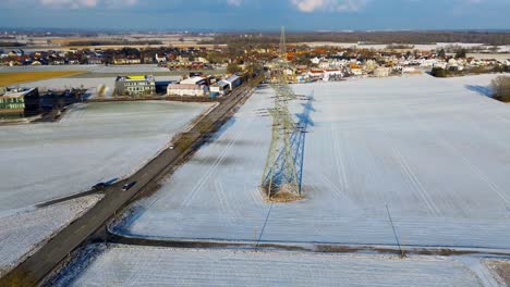 Wintry-Village-Panorama-with-Snow-Fields-and-Central-Electricity-Pylon