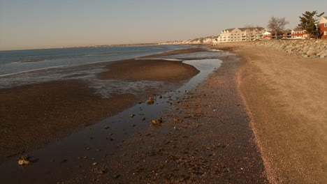 Drone-flying-fast-over-a-beach-with-a-person-in-the-background