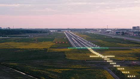 Flug-Um-Die-Aufsetzzone-Der-Landebahn-Des-Flughafens-Tallinn-Im-Sonnenuntergang-Mit-Eingeschalteter-Anflugbeleuchtung-Und-Rollenden-Blitzen