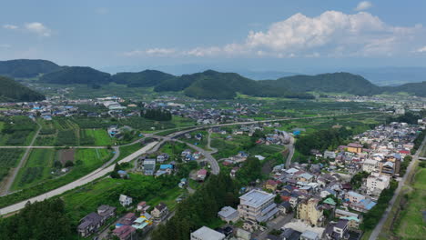 Aerial-view-backwards-over-countryside-homes-and-plantations,-in-Nagano,-Japan