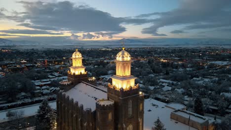 Aerial-pullback-from-Logan-Utah-LDS-temple-with-panoramic-views-of-snow-covered-city-at-dusk