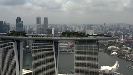 Aerial-Panning-Shot-of-Marina-Bay-Sands-Hotel-Rooftop-with-Scenic-Cityscape-Views-in-Singapore