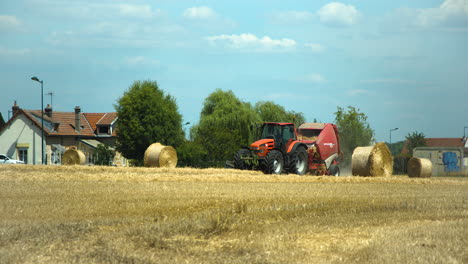 Tractor-Rojo-Con-Gran-Máquina-Empaquetadora-Recogiendo-Hierba-Amarilla-Seca-Del-Campo