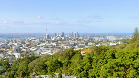 Eine-Reiseaufnahme-Der-Skyline-Von-Auckland-In-Neuseeland-Aus-Der-Ferne-Mit-üppiger-Vegetation-Im-Blick-An-Einem-Sonnigen-Und-Klaren-Nachmittag-Mit-Blauem-Himmel