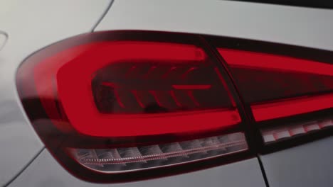Close-up-of-shiny-red-tail-light-of-car,-light-reflection-on-painted-surface