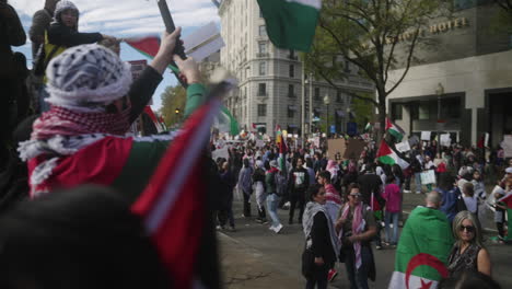 An-Arab-Man-Waves-a-Palestinian-Flag-While-a-Large-Crowd-of-Pro-Palestine-Protestors-Walks-in-Front-of-Him