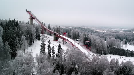 Fast-aerial-tracking-shot-of-Tehvandi-ski-jump-tower-in-Otepää,-Southern-Estonia-during-very-cold-winter-with-snow