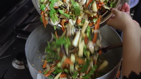 Cooking-chef-adding-vegetable-stir-fry-in-pot-with-onions