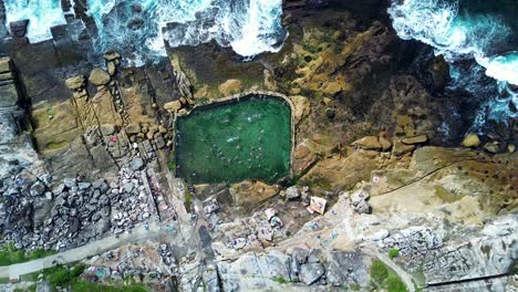 Drone-aerial-people-swimming-in-Mahon-rock-pool-bath-Maroubra-beach-rocky-ocean-headland-Randwick-Sydney-city-travel-tourism-Australia
