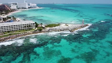 Cancun-coastline-with-clear-turquoise-waters-and-a-lighthouse,-aerial-view