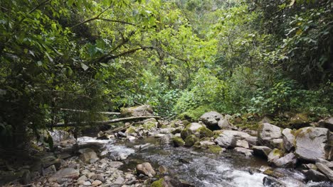 Panorámica-A-Través-Del-Río-Tropical-Que-Corre-A-Través-De-Terrenos-Del-Valle-Sembrados-De-Rocas-Inundadas-En-El-Valle-De-Cocora,-Colombia
