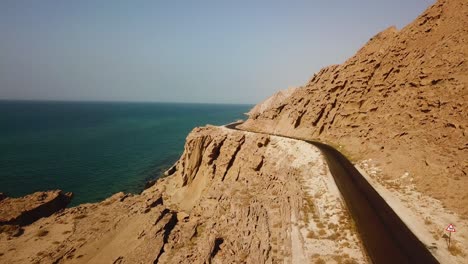 Asphaltstraße-Neben-Dem-Strand-Winderosion-Felsmassiv-Berg-Klippe-Strand-Küstenlandschaft-Des-Ozeans-Links-Berg-Rechts-Wunderbares-Roadtrip-Konzept-Der-Reise-Sommerferien-Iran