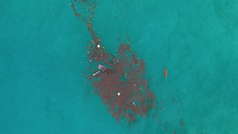 Drone-bird's-eye-view-rotate-ascend-above-trash-marine-debris-floatsam-patch-in-middle-of-ocean-water