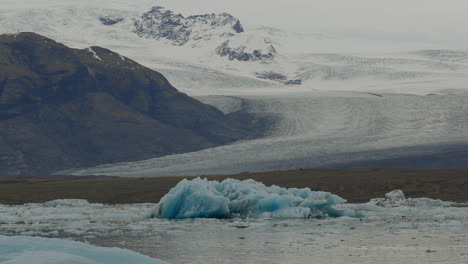 Glacier-Lagoon-in-Jökulsárlón,-Iceland,-featuring-glaciers-floating-in-icy-waters-with-snowy-mountains-in-the-background