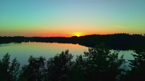 Beautiful-Sunset-Over-a-Calm-Lake-with-Silhouette-of-Trees-from-an-Aerial-Drone-Dolly-Shot