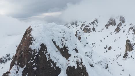 Snow-covered-Ciucas-Mountains-peaks-under-overcast-sky,-aerial-view