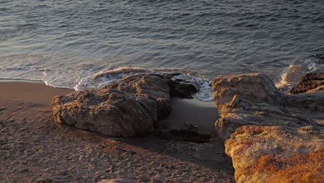 Kleine-Felsen-Mit-Wellen,-Die-Bei-Sonnenuntergang-Am-Meer-Hereinbrechen