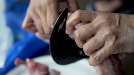 A-traditional-vegetable-cutter,-known-as-"Aruvamanai,"-is-employed-for-slicing-raw-chicken-meat,-showcasing-the-essence-of-meal-preparation-and-culinary-expertise-in-cooking