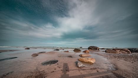 Clouds-move-fast-above-the-sandy-beach-and-low-waves-in-the-timelapse-video