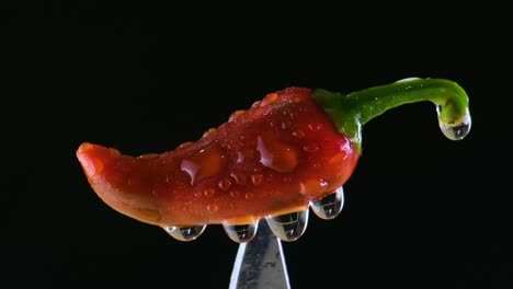 Extreme-closeup-shot-of-a-red-chilli-on-top-of-a-knife-with-black-background