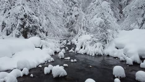 Low-and-close-fly-over-winter-river-with-mounds-of-snow