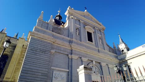 Blick-Nach-Oben-Zur-Riesigen-Kirche-Catedral-De-La-Almudena-Im-Stadtzentrum-Von-Madrid,-Katholisches-Denkmal-Am-Blauen-Himmel-Tagsüber