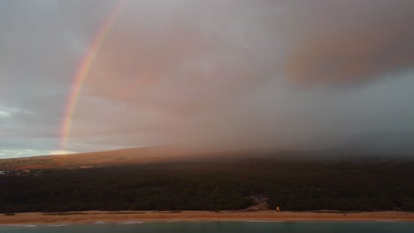 Cinematic-slow-aerial-shot-of-a-rainbow-over-beautiful-South-Maui-beach,-Maui-County,-Hawaii
