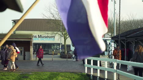 Close-up-of-Dutch-flag-with-tourist-walking-in-background-in-front-of-Zaans-Museum