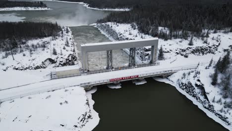 Aerial-Slow-Orbit-Drone-Shot-Rushing-Water-Notigi-Hydroelectric-Power-Lake-Dam-in-Snowy-Northern-Winter-Manitoba-Canada