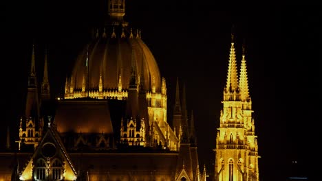 Blick-Auf-Die-Innenstadt-Von-Budapest-Mit-Parlamentsgebäude-Und-Donau-Bei-Nacht,-Gotische-Architektur,-Lichtreflexionen,-Mittlere-Aufnahme-Mit-Türmen