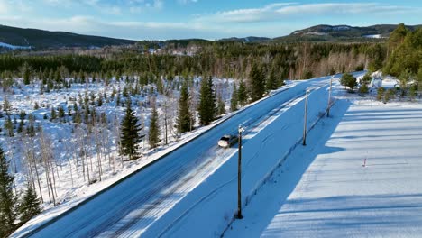 Car-driving-on-snowy-road-through-winter-forest-in-Skorped,-Sweden,-clear-day