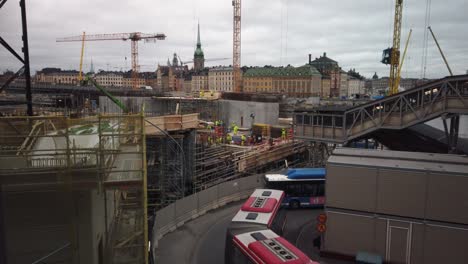 Buses-turn-on-narrow-road-by-construction-site-in-central-Stockholm,-Sweden