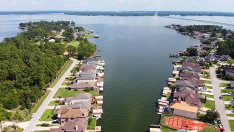 An-aerial-shot-of-lakeside-homes,-near-a-golf-course,-on-a-sunny-day,-recorded-at-60-frames